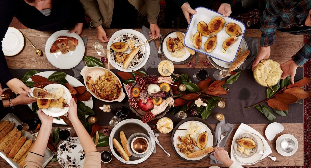 many hands reaching for food at Thanksgiving table