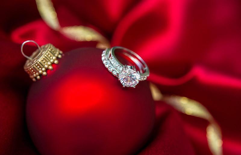 red glass ball Christmas ornament with an engagement ring balanced on it