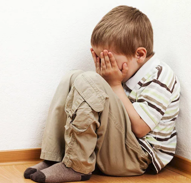 little boy scrunched up, hiding face with hands, probably crying