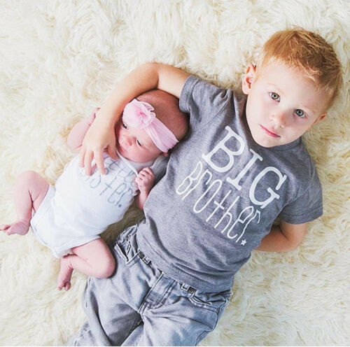 red haired preschool-age boy lies on floor with newborn sister