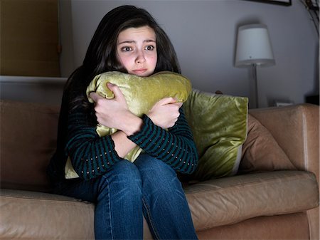 scared preteen girl hugging throw pillow